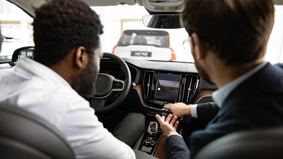 A salesman showing another man the interior of a car in a vehicle showroom